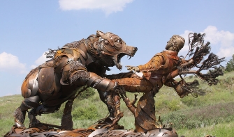 a large life size assembled metal sculpture of the frontiersman hugh glass being attacked by a grizzly bear